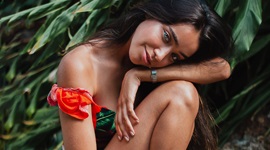 A photo of a beautiful Latina sitting on a rock